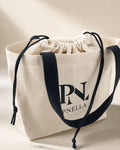 PNELLA signature cream tote bag with black handles and drawstring closure